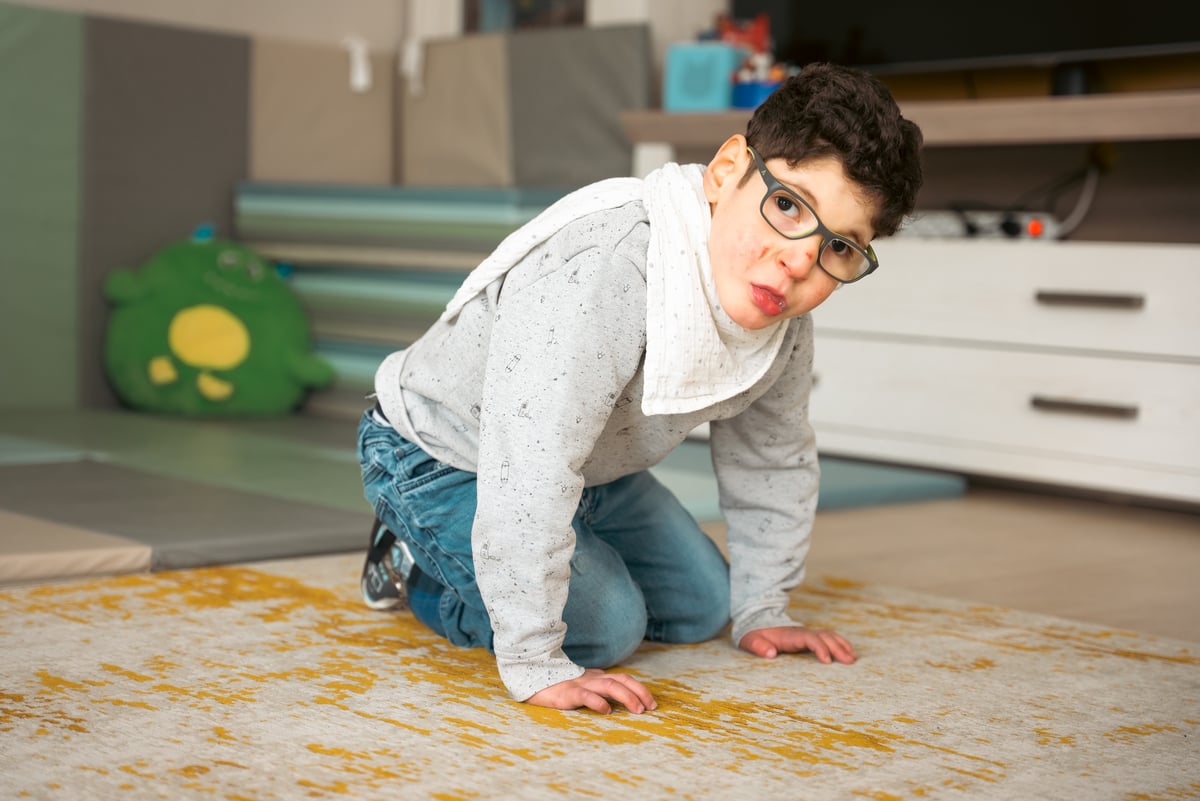 En liten pojke sitter på mattan i hemmet