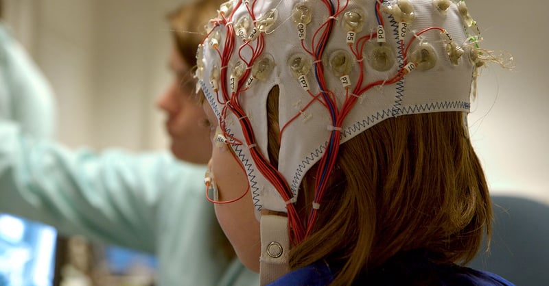 För en vetenskaplig undersökning är en flicka ansluten med kablar till en dator, EEG för forskning.
