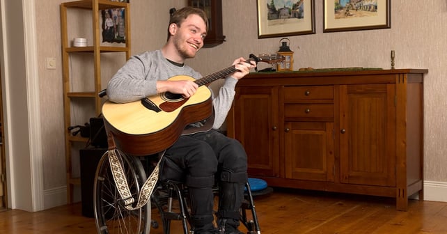 Young man plays his guitar while sitting in his wheelchair
