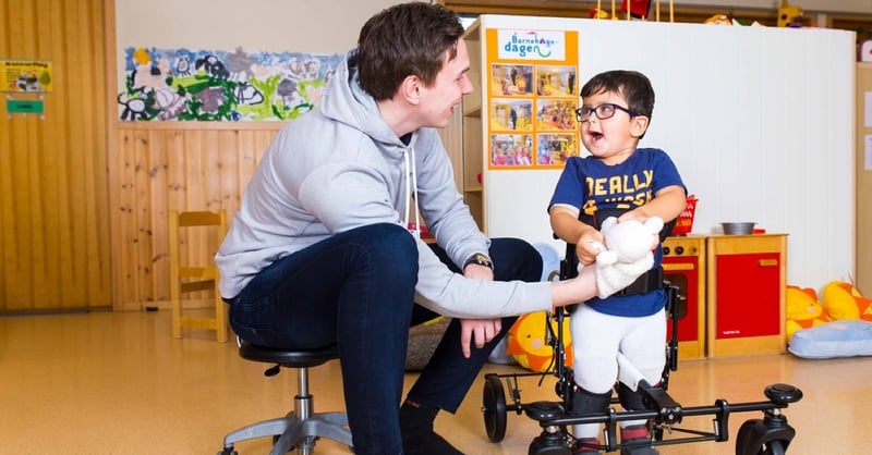 Fysioterapeut og en gutt med nedsatt funksjonsevne i gangtreningshjelpemiddel