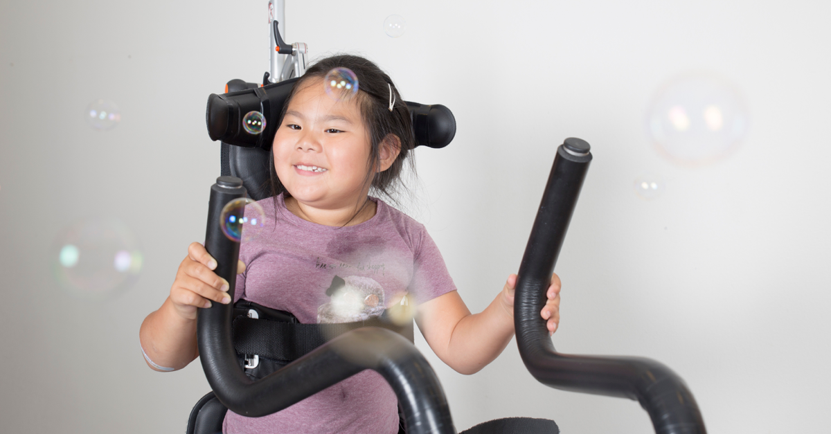 Girl in assistive device and bobles!  Hwat do we know about physical activity and cerebral palsy?