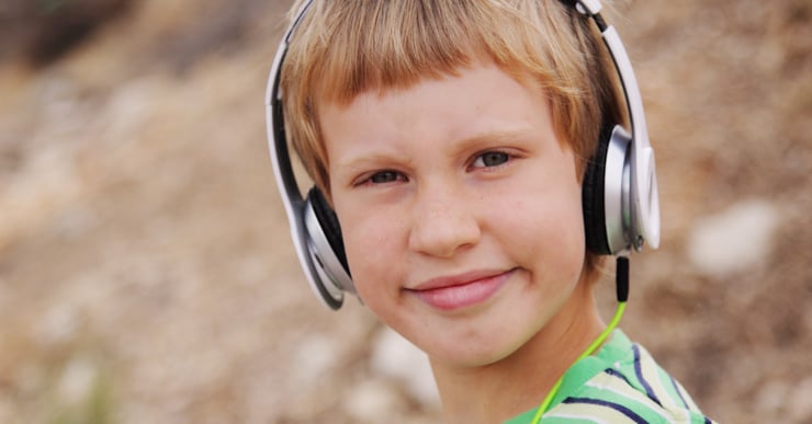 Gutt med headset som hører på musikk. Hvordan kan musikkterapi hjelpe barn med funksjonsnedsettelser? 
