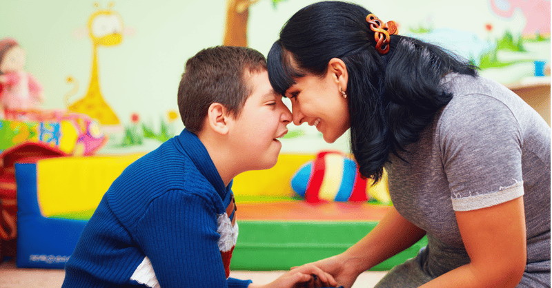 Gutt med funksjonsnedsettelse og smilende kvinne på et lekerom. Hvilke kartleggingsverktøy finnes det for å undersøke og vurdere personer med cerebral parese?