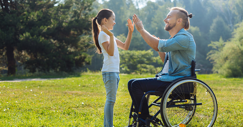 Young father with mobility impairment giving his little daughter a high five.