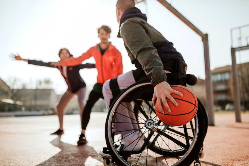 Man in wheelchair playing basketball with friends on sports court